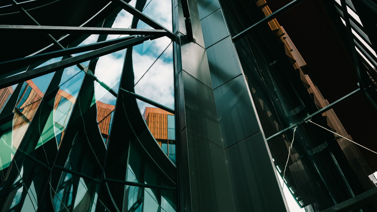 Edificio moderno de vidrio con reflejos dinamicos y cielo brillante, imagen para guia de 12 clausulas clave del contrato de pozo